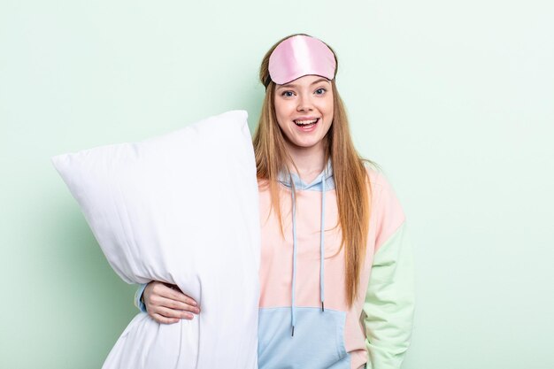 Redhair woman looking happy and pleasantly surprised pajamas and pillow concept