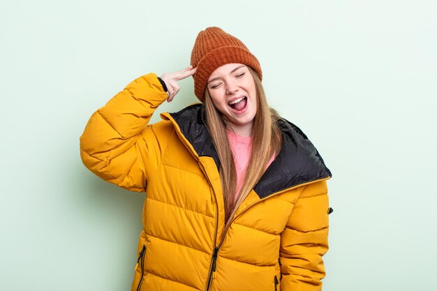 Photo redhair woman looking unhappy and stressed suicide gesture making gun sign winter concept