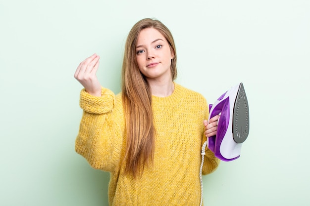 鉄の服のコンセプトを支払うようにあなたに言ってcapiceまたはお金のジェスチャーを作るRedhairの女性