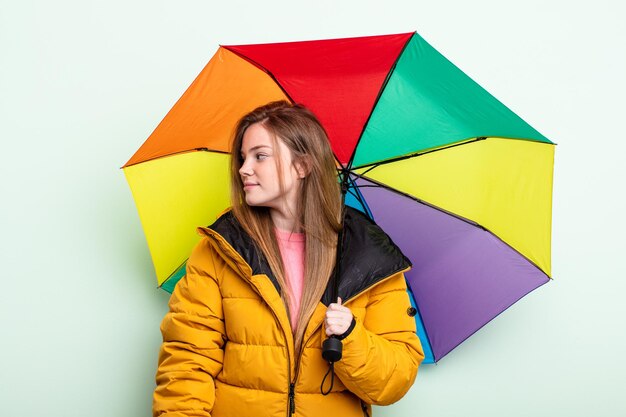 Redhair woman on profile view thinking imagining or daydreaming umbrella concept