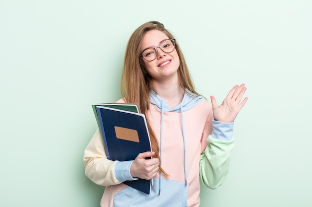 喜んで笑って、手を振って、あなたを歓迎し、挨拶する赤毛の女性。学生の概念