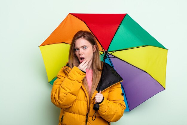 Redhair woman with mouth and eyes wide open and hand on chin umbrella concept