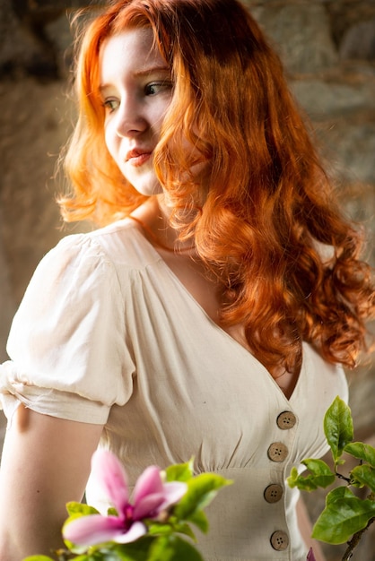 로맨스를 주제로 한 프랑스 전통 가옥에서 흰색 나이트 드레스를 입은 오래된 창문 근처에 있는 빨간 머리의 아름다운 소녀
