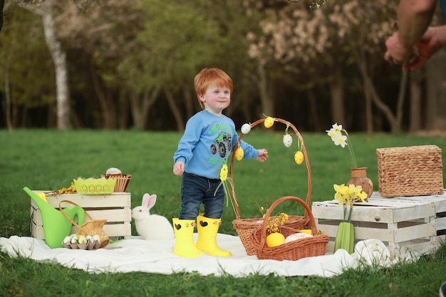 Redhaired boy is playing in the spring park with rabbits and there is a lot of Easter decor