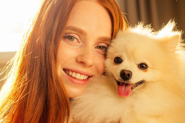 Redhaired ginger girl hugging her cute dog in living room