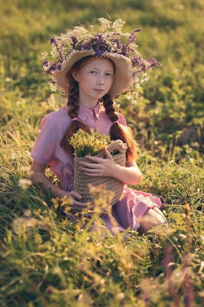 牧草地の夕暮れ時の帽子をかぶった赤髪の少女