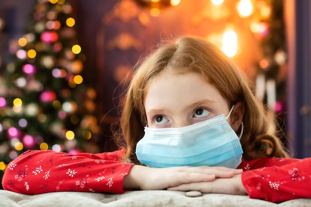 Photo redhaired girl in a medical mask is sad on christmas eve