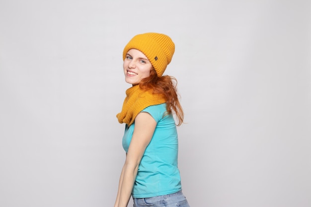 Redhaired girl in a warm hat on a light background