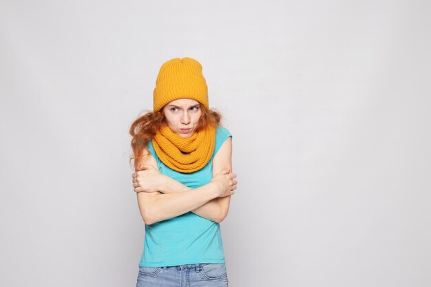 Redhaired girl in a warm hat on a light background