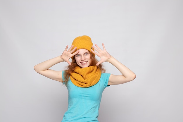 Redhaired girl in a warm hat on a light background