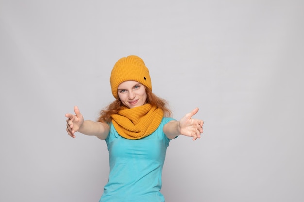 Redhaired girl in a warm hat on a light background