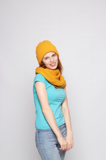 Redhaired girl in a warm hat on a light background