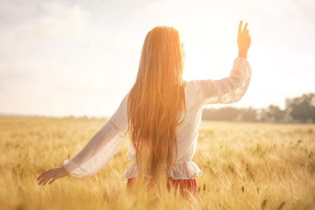 Redhaired girl in a wheat field at sunset Beautiful woman in golden field at sunset Backlit warm tones