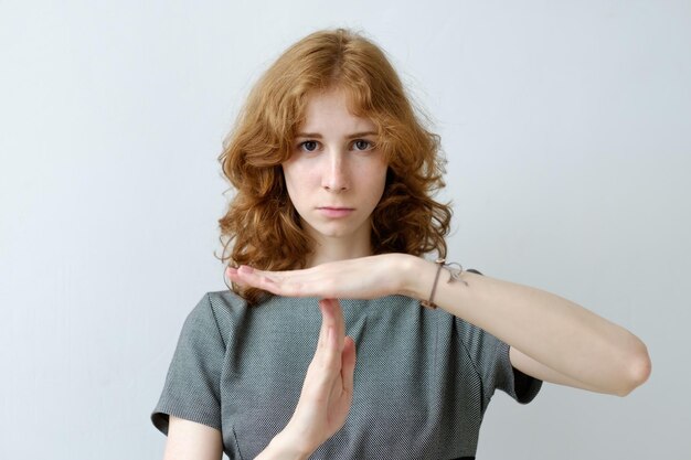 A redhaired girl with curly hair and freckles shows a sign of a timeout Pause in work or relationship