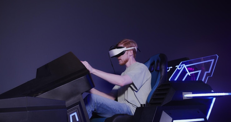 Photo a redhaired guy in virtual reality glasses controls the simulator in 5d