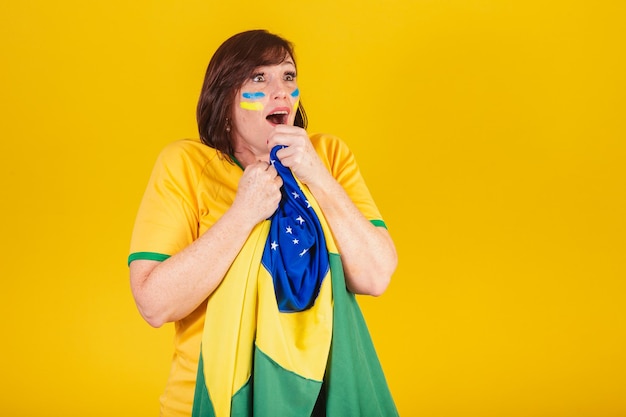 Redhaired woman brazilian soccer fan fluttering with the flag of brazil surprised