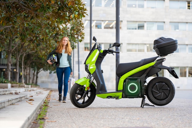 Redhaired woman is going to ride an electric motorbike