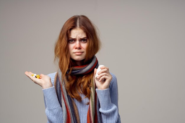 Redhaired woman neck scarf pills in hand isolated background