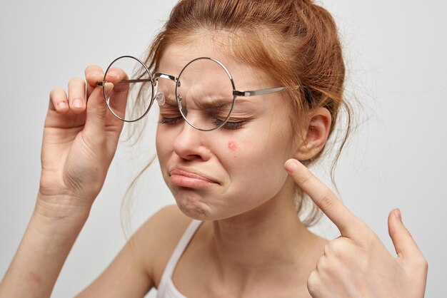 Redhaired woman wearing glasses pimple on face dermatology skin
care