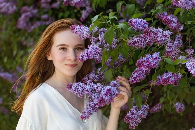 여름에 흰 꽃이 만발한 덤불의 배경에 redhaired 어린 소녀