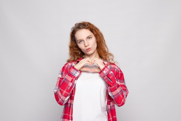 Redhaired young girl in a plaid shirt on a white background with a place for text