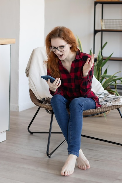 自宅のキッチンで携帯電話で話している赤毛の少女