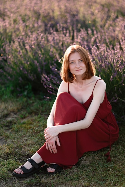 A redhaired young girl without makeup is resting in a lavender field Summer vacation and travel time