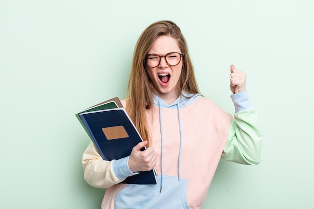 Redhairvrouw die agressief met een boze uitdrukking schreeuwt. studentenconcept