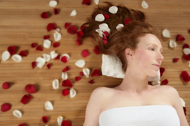 Redhead beautiful woman, rose petals on hair