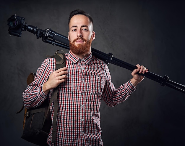 Redhead bebaarde freelance fotograaf met statief en rugzak.