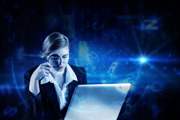 redhead businesswoman using her laptop against blue background with letters