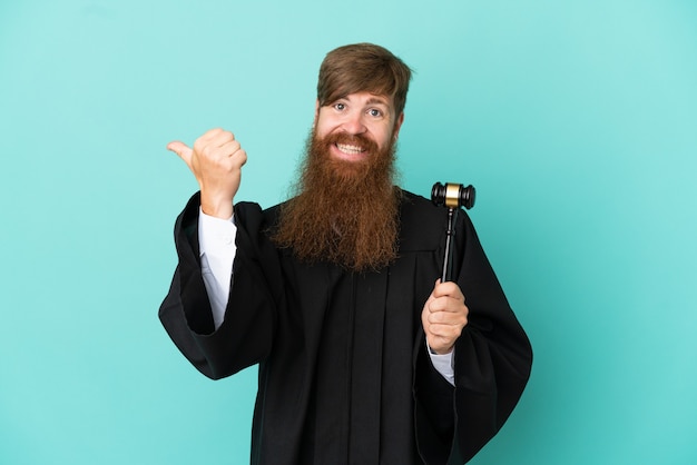 Redhead caucasian judge man isolated on blue background pointing to the side to present a product
