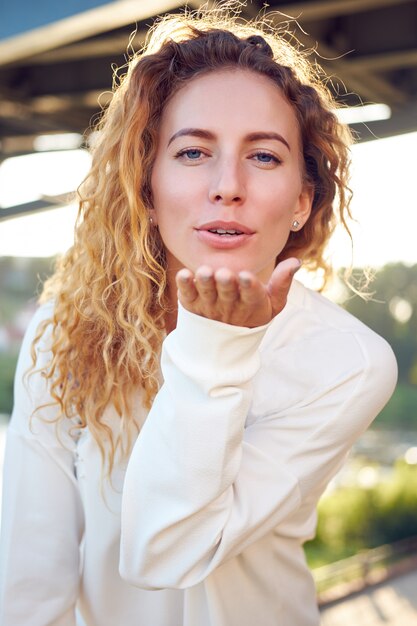 Redhead curly young cute girl blowing a kiss