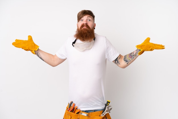 Redhead electrician man with long beard over isolated white wall having doubts with confuse face expression