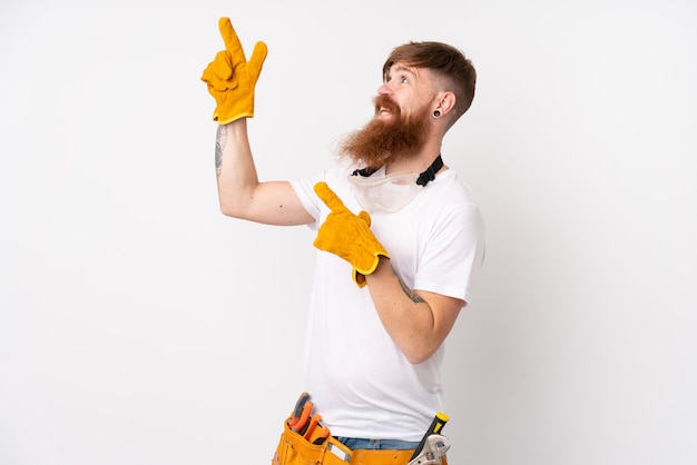 Рыжий электрик человек с длинной бородой над изолированной белой стеной, указывая указательным пальцем отличная идея