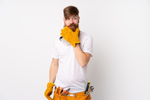 Redhead electrician man with long beard over isolated white wall thinking an idea