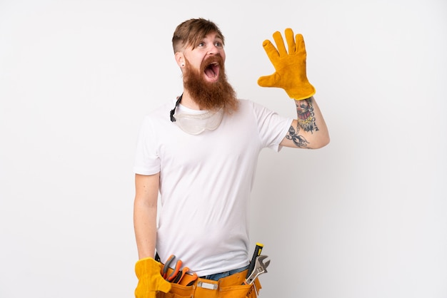 Redhead electrician man with long beard over white wall shouting with mouth wide open