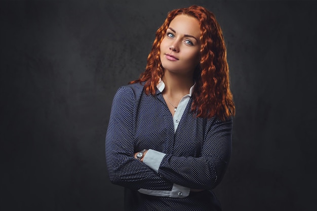 Redhead female supervisor dressed in an elegant suit over grey background.