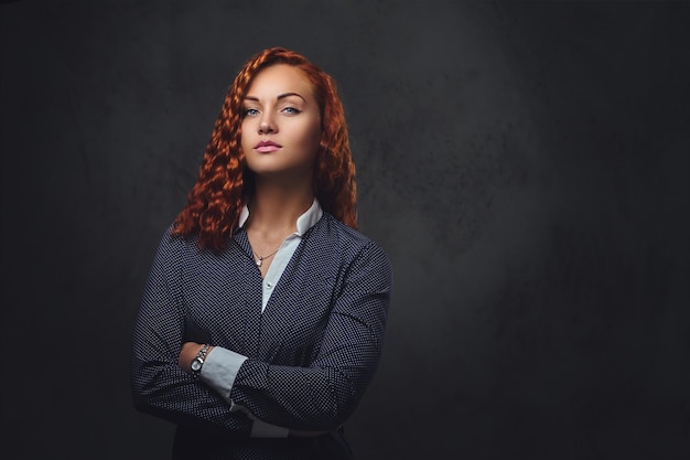 Redhead female supervisor dressed in an elegant suit over grey background.