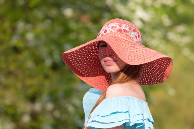 Redhead ginger girl dressed in color hat and blue dress summer portrait