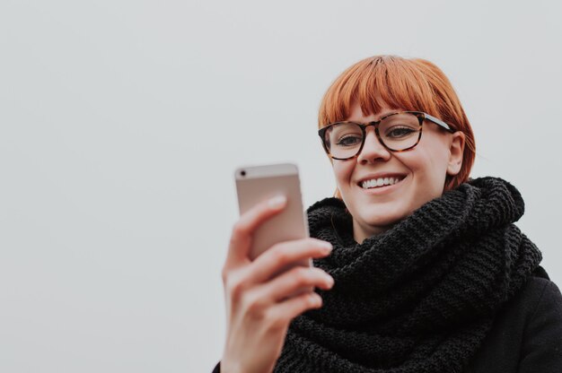 Redhead girl checking phone outside