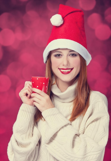 Redhead girl in christmas hat with cup