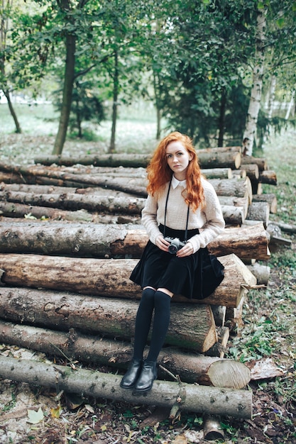 redhead girl holding camera in autumn park 