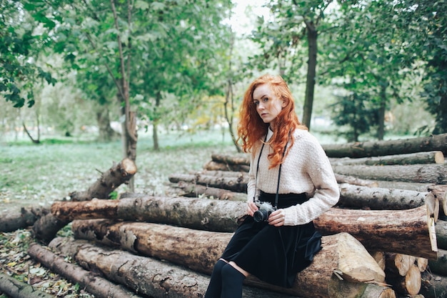 redhead girl holding camera in autumn park 