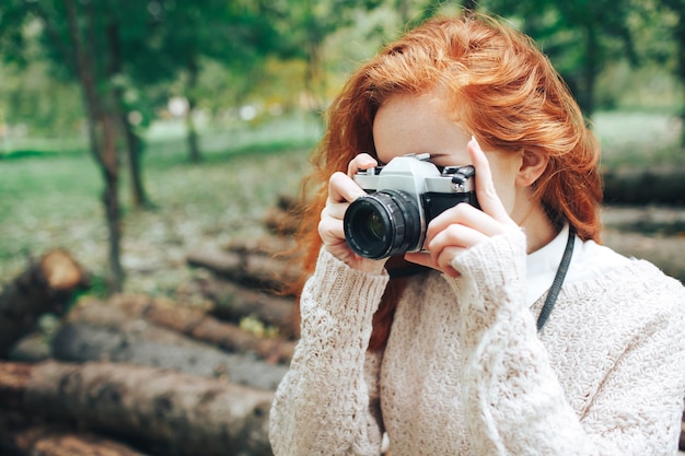 Photo redhead girl holding camera in autumn park