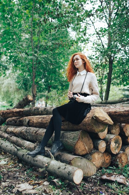 redhead girl holding camera in autumn park 