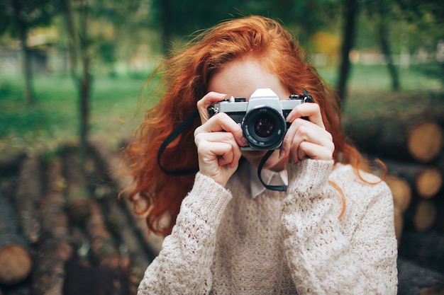 Redhead girl holding camera in de herfst park