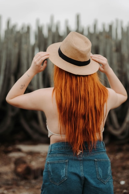 Redhead girl putting on her hat in the desert