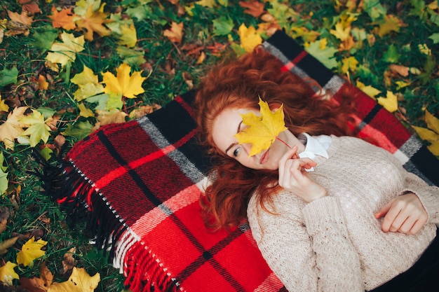 Foto ragazza di redhead sul plaid rosso in autunno parco