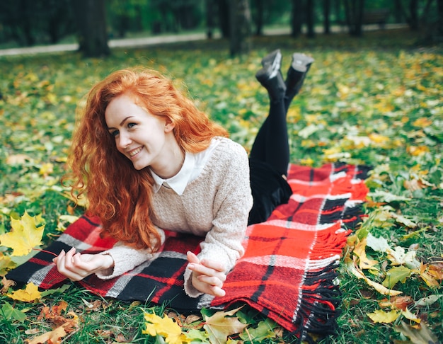 redhead girl on red plaid in autumn park 